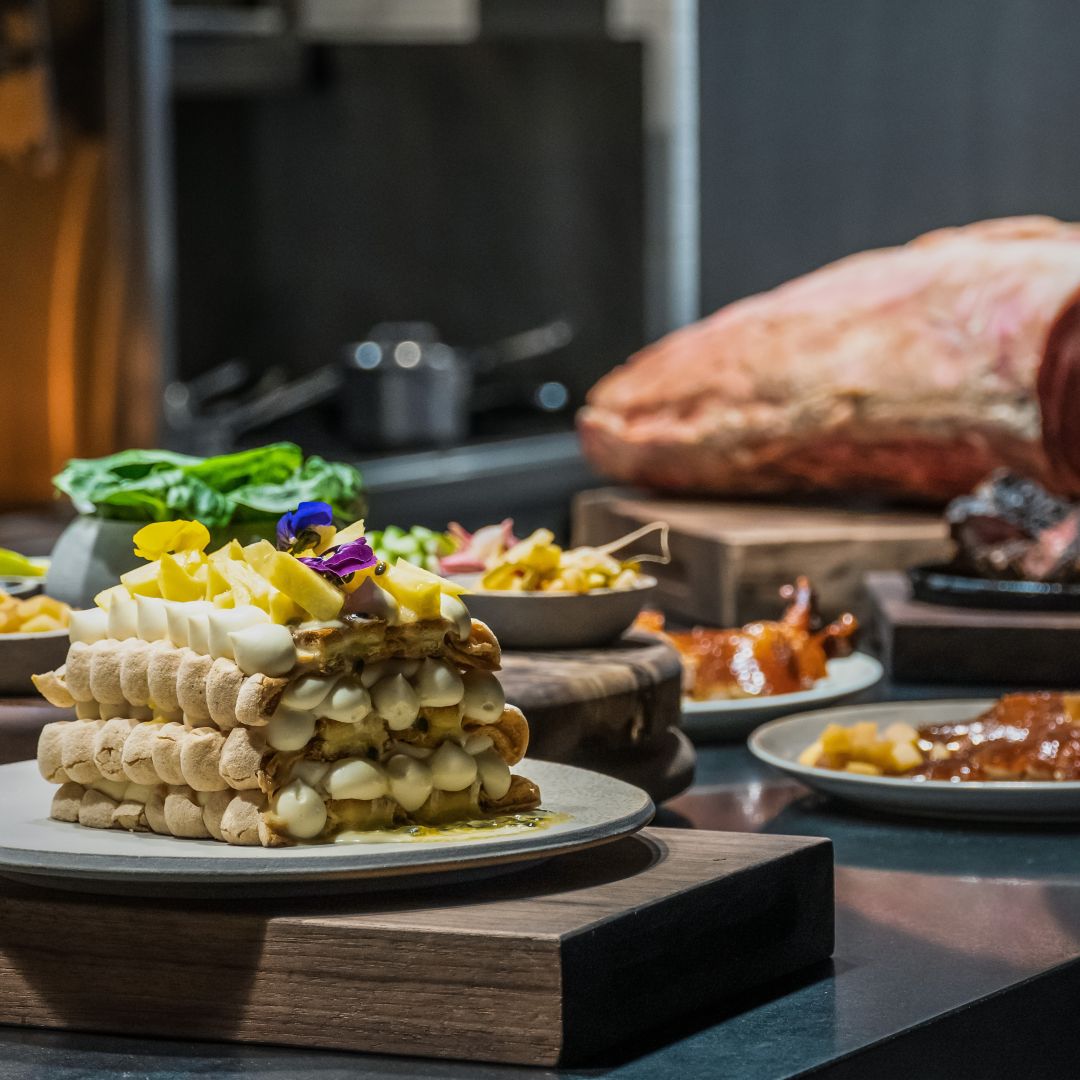 A table with a layered dessert, roasted meat, and various dishes, including a salad.
